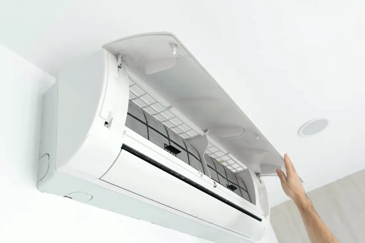 Hand opening the cover of a wall-mounted ductless air conditioner